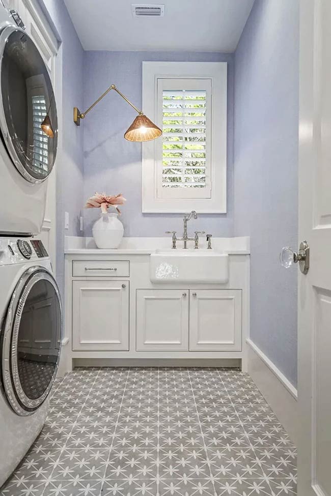 A narrow laundry space in Santa Rosa Beach uses soft coastal colors to create a serene environment. Graphic floor tiles add subtle pattern, while a wall sconce provides adjustable light. The stackable washer/dryer is tucked neatly, and open shelves keep supplies accessible. The gentle palette makes chores feel less like work and more like a calm, organized routine.