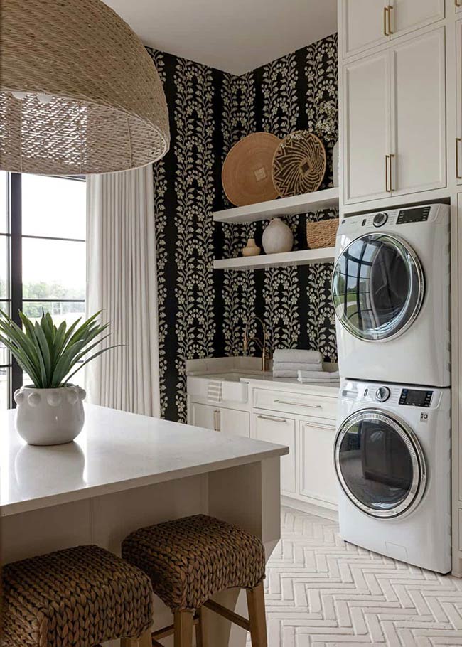 A black and white laundry room can feel clean, bold, and inviting all at once. White cabinets with black handles contrast beautifully with patterned cement floor tiles, while a woven pendant light adds texture and warmth. The room manages to be both functional and stylish, with plenty of storage for detergents and linens. Open shelving can display decorative baskets or jars, giving the space personality without clutter. This design shows that even a monochrome palette can feel vibrant when textures and small details are carefully layered.