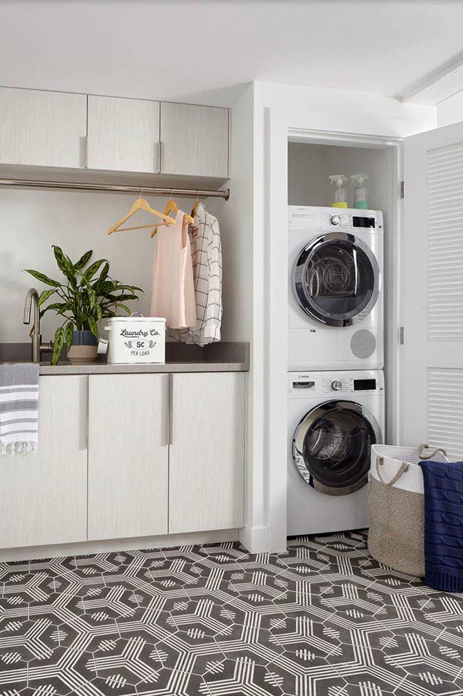 Some laundry rooms hide appliances for a sleek, uncluttered look. A Redwood City garage space uses dark, textured laminate cabinets topped with gray quartz, concealing a stackable washer and dryer behind louvered doors. Charcoal-and-white hex tiles on the floor add visual interest, while soft eggshell walls keep the room feeling bright. This setup keeps the laundry area tidy and cohesive with the rest of the home’s contemporary style, proving that hidden solutions can be both practical and beautiful.