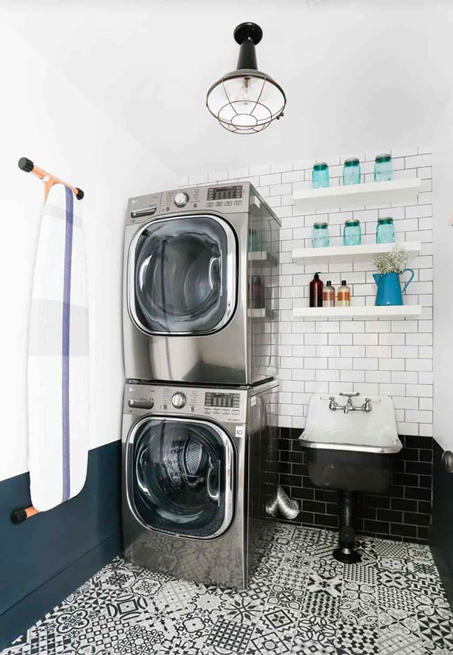 Even 50 square feet can hold all laundry essentials. A stacked LG washer and dryer, wall-mounted ironing board, floating shelves, and a utility sink make the room highly practical. Black-and-white floor tiles add contrast, and vertical space is used smartly for storage. Small rooms can be both functional and attractive when every inch is planned carefully.