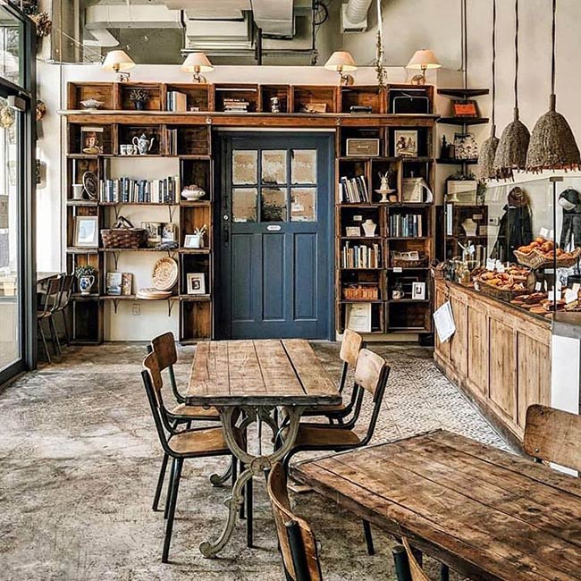 That dark blue door frames the back of the shop perfectly. The wall is filled with rustic wooden crates that hold books and vintage decorations, giving the space a cozy, old-fashioned general store vibe.
