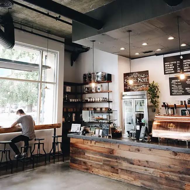Mixing a smooth concrete top with rough wood planks creates a very stylish counter. It is a simple, rugged look that works well with the black metal stools.