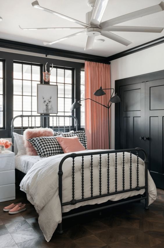 The black window frames and heavy metal bed give this room a strong look. Soft pink curtains and that fuzzy pillow help balance out the dark colors. It is a cool way to style a pink and black bedroom.