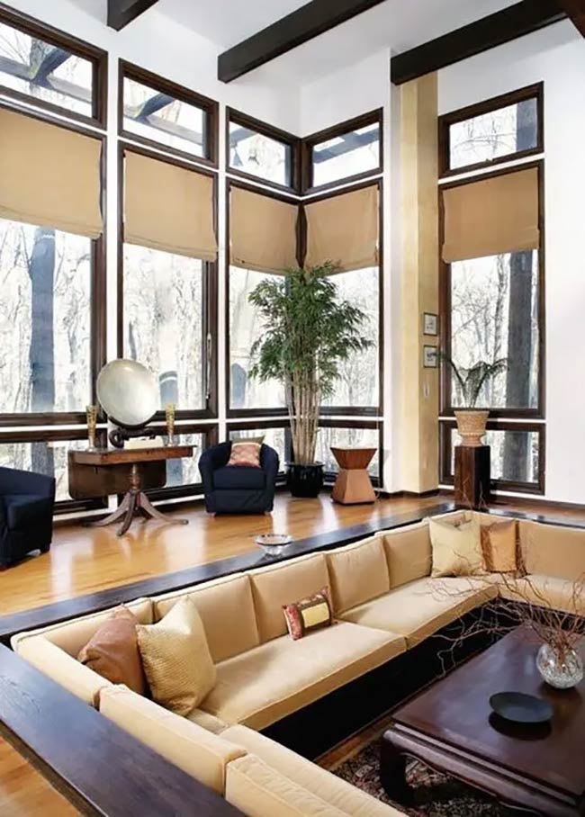 The giant windows in this room show the whole forest outside, right next to the sunken conversation pit.