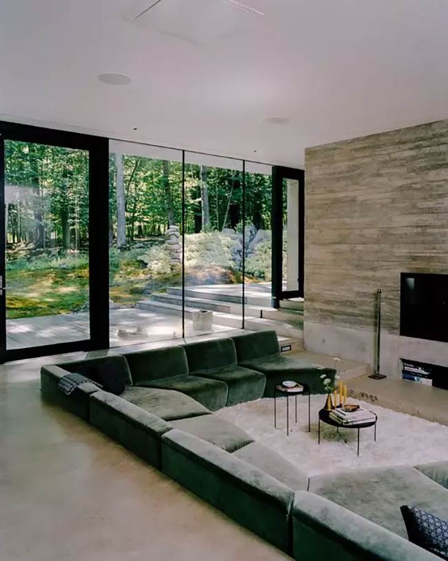The soft green sofa looks nice against the hard concrete wall in this sunken living room.