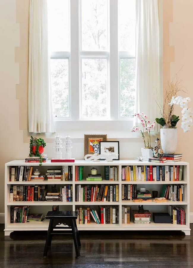 This sturdy white unit adds three rows of storage under the tall, elegant window. It works great for organizing heavy books and showing off decorative items like the white pagodas.